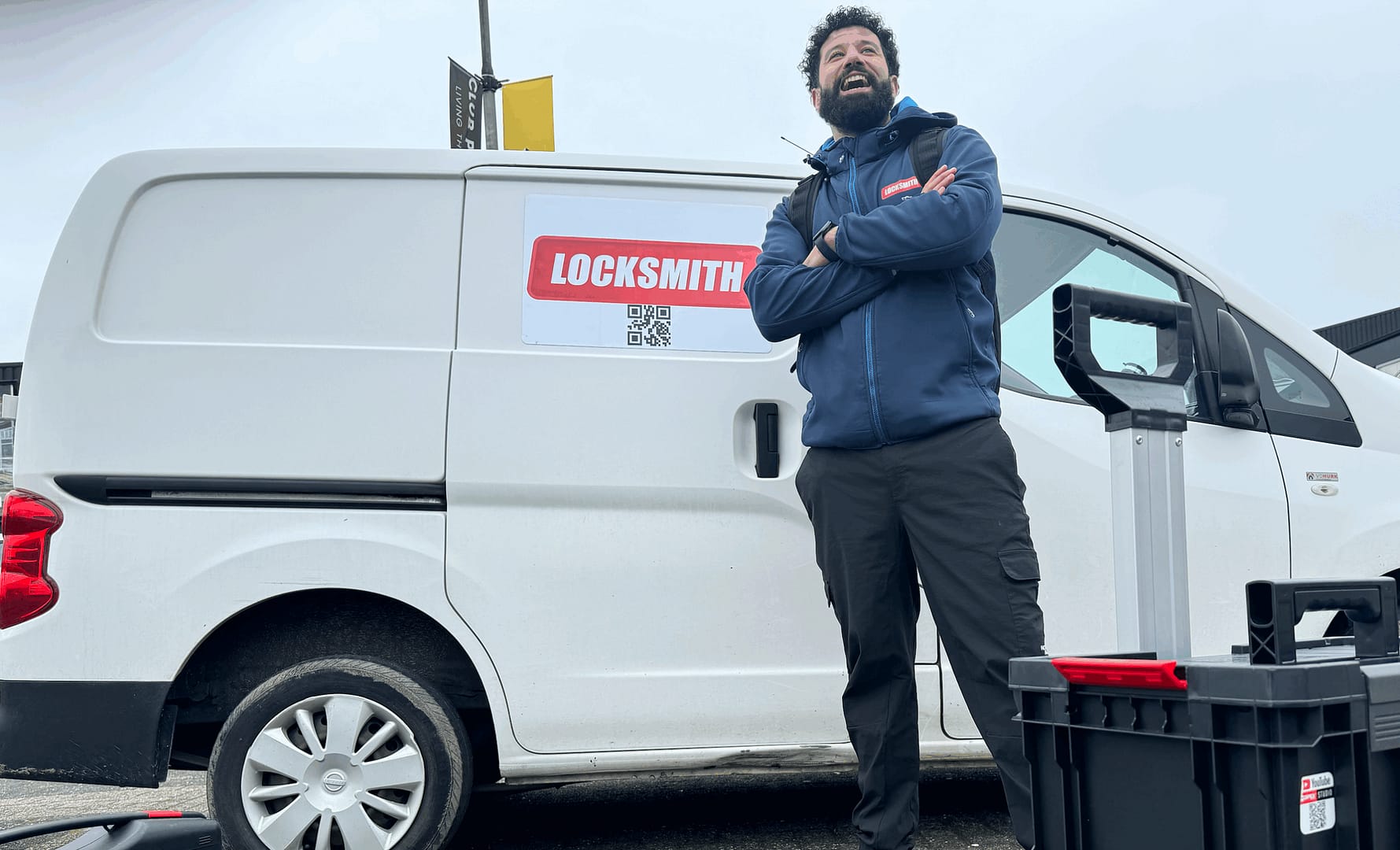 Slotenmaker leunt op bestelwagen met bedrijfslogo.