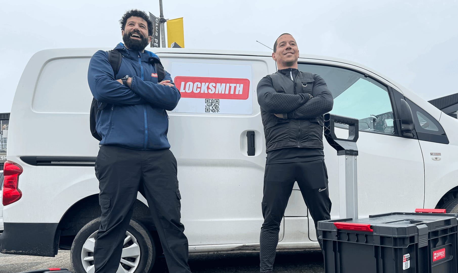 Slotenmakers bij bedrijfswagen met gereedschapskisten.