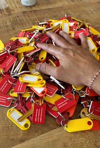 Hand boven stapel kleurrijke sleutelhangers op tafel