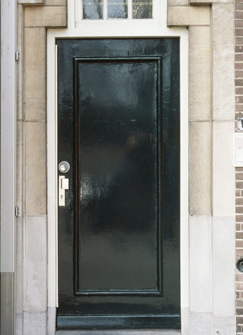 Zwarte voordeur van een bakstenen huis.