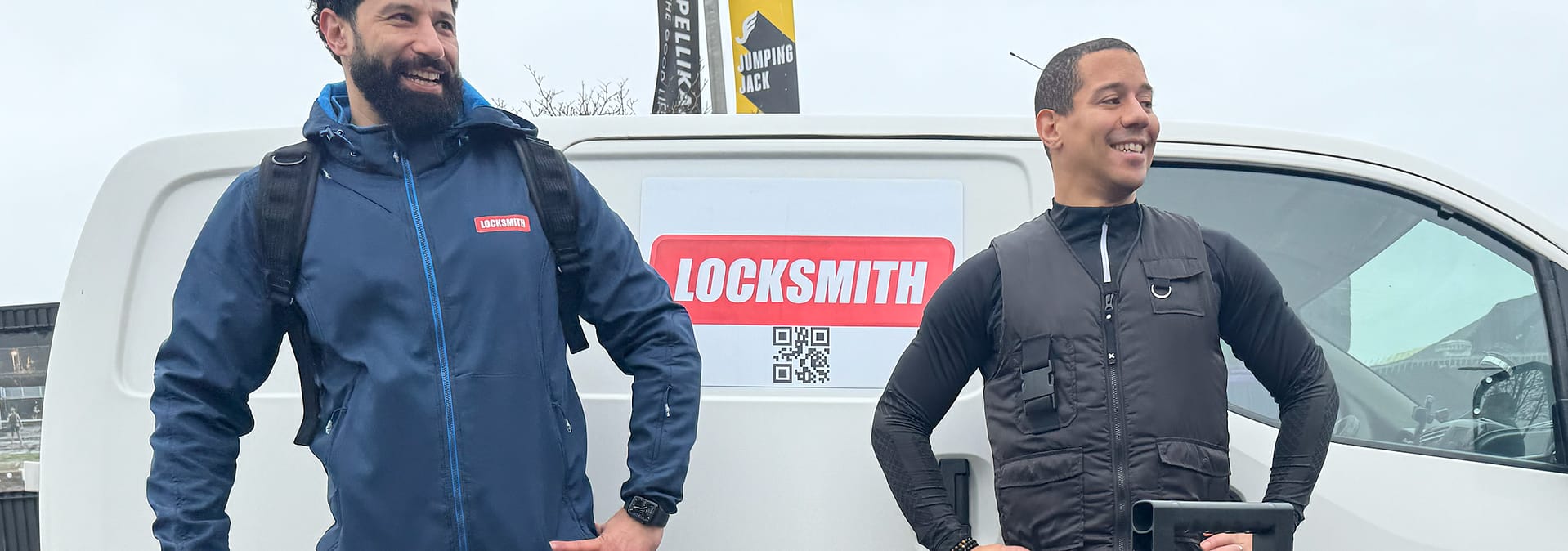 Twee slotenmakers naast bedrijfswagen met logo.